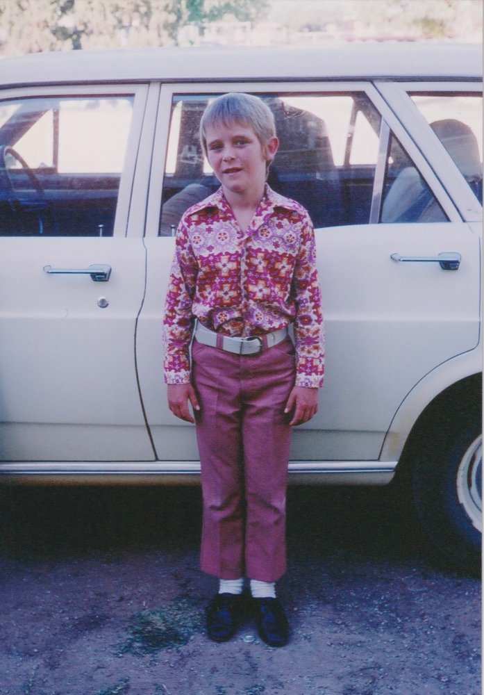 A boy in his best clothes by the family car